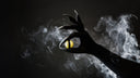 A hand with claws holds a bon bon with a cat eye design