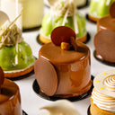 Assorted small Norman Love cakes with different designs on a white surface