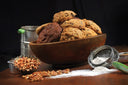 Wooden bowl filled with cookies on a wooden surface with ingredients around