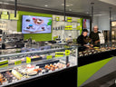 Interior of a modern bakery with display cases, refrigerators, and people working.