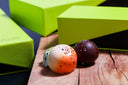 Two colorful bon bons on a wooden surface with green geometric shapes in the background