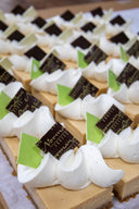 Delicate dessert bars with white meringue, chocolate flags, and green triangles on a white surface.