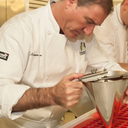 Chef Norman Love in a kitchen using a tool to prepare chocolate