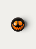 Norman Love Confections Blood Orange dark chocolate truffle with a hand-painted orange jack-o-lantern face design.
