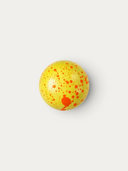 Norman Love Confections Caramel Apple chocolate truffle with a bright yellow shell and orange splatter design