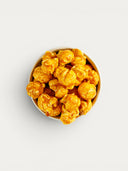 Norman Love Confections golden caramel popcorn with sea salt in a white bowl, top-down view.