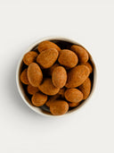 Norman Love Confections dark chocolate candied almonds dusted in cocoa powder in a white bowl.