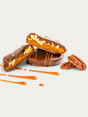 Norman Love Confections Dark Chocolate Caramel Pecan Turtles with caramel drizzle and pecans.