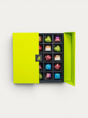 Norman Love Confections assorted dark chocolates in a bright green box, featuring heart and square shapes with colorful drizzles and speckles.