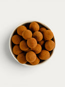 Norman Love Confections dark chocolate candied hazelnuts dusted with cocoa powder in a white bowl.