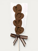 Norman Love Confections dark chocolate LOVE pop, individually wrapped with a brown and gold ribbon.