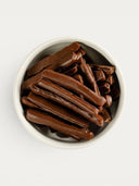 Norman Love Confections dark chocolate-covered orange sticks in a white bowl.