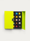 Norman Love Confections bright lime green box filled with 16 assorted gourmet chocolates, each uniquely decorated.