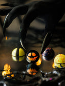 Norman Love Confections Halloween chocolates with a jack-o-lantern design held by a spooky clawed hand.