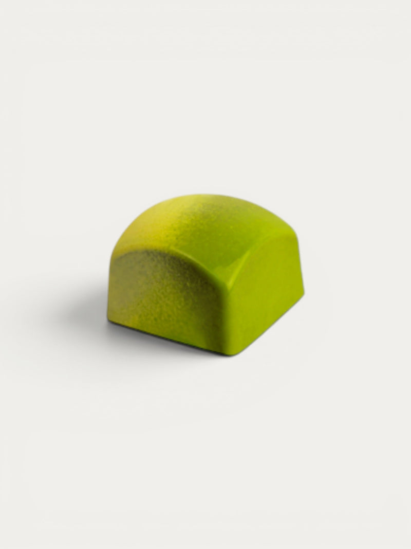 Norman Love Confections lime green chocolate truffle with a dark chocolate center and a smooth, glossy finish.