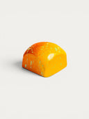 Norman Love Confections Mango chocolate truffle with orange and yellow marbled shell and green speckles.