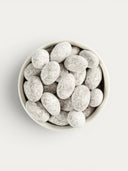 Norman Love Confections milk chocolate candied almonds dusted with powdered sugar in a white bowl.