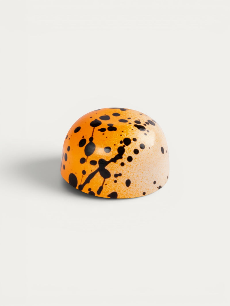 Norman Love Confections Passion Panna-Cotta chocolate with orange and white chocolate shell splattered with black.