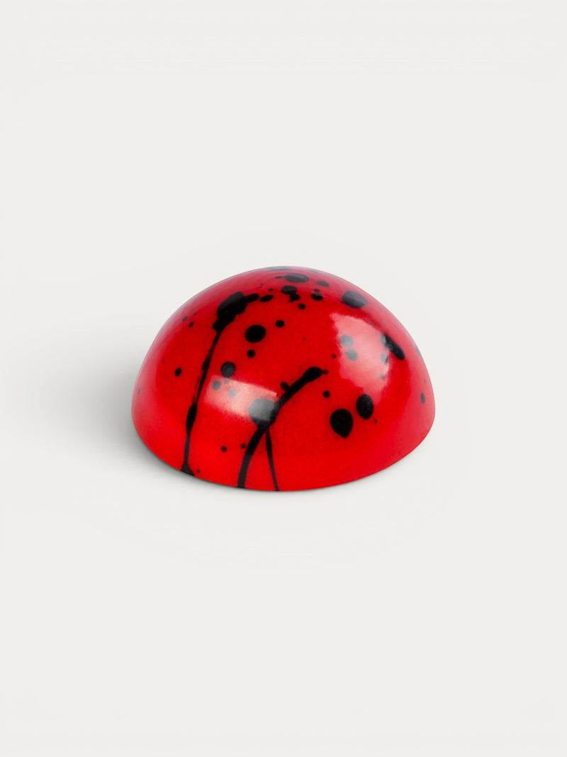 Norman Love Confections red chocolate dome with black splatter detail, strawberry filling.