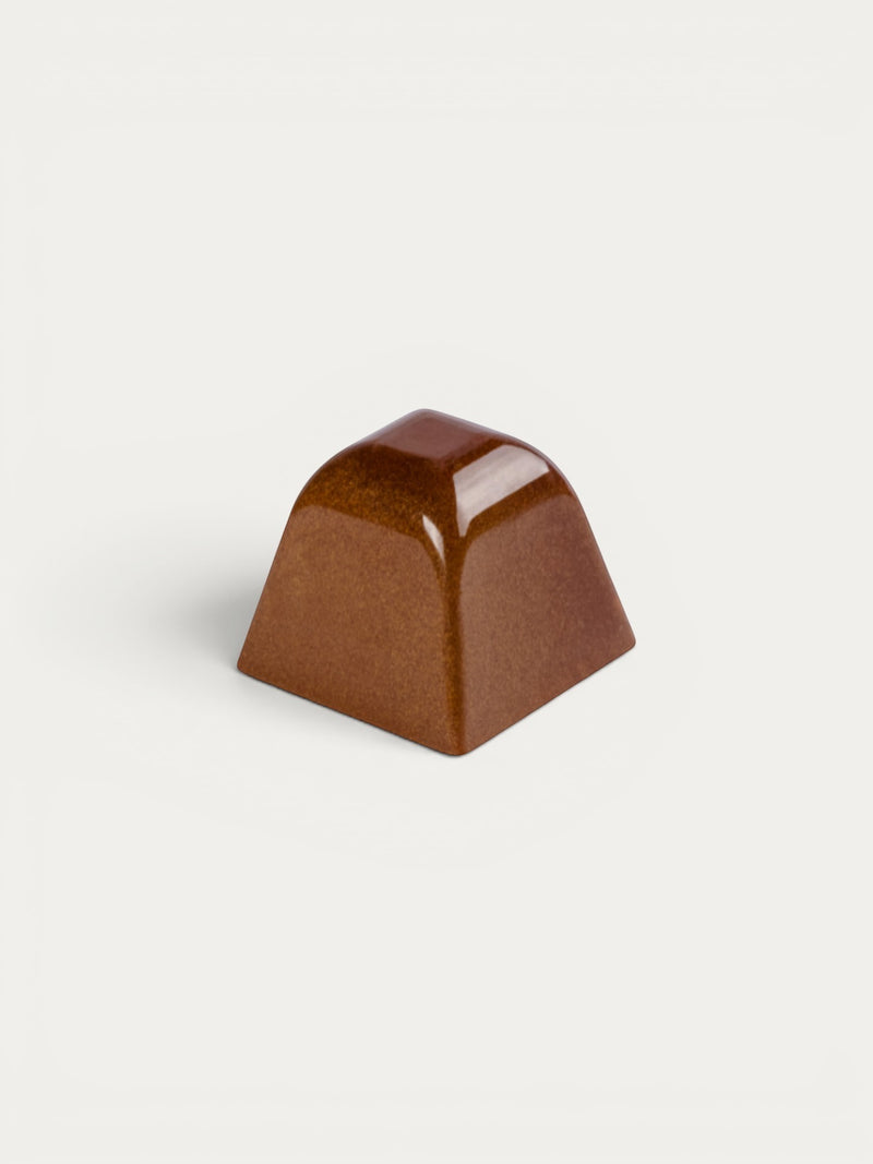 Norman Love Confections Tahitian Caramel chocolate pyramid with a glossy milk chocolate shell and buttery caramel center.