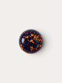 Norman Love Confections Vanilla Caramel chocolate sphere with a glossy dark blue shell and bright orange splatter