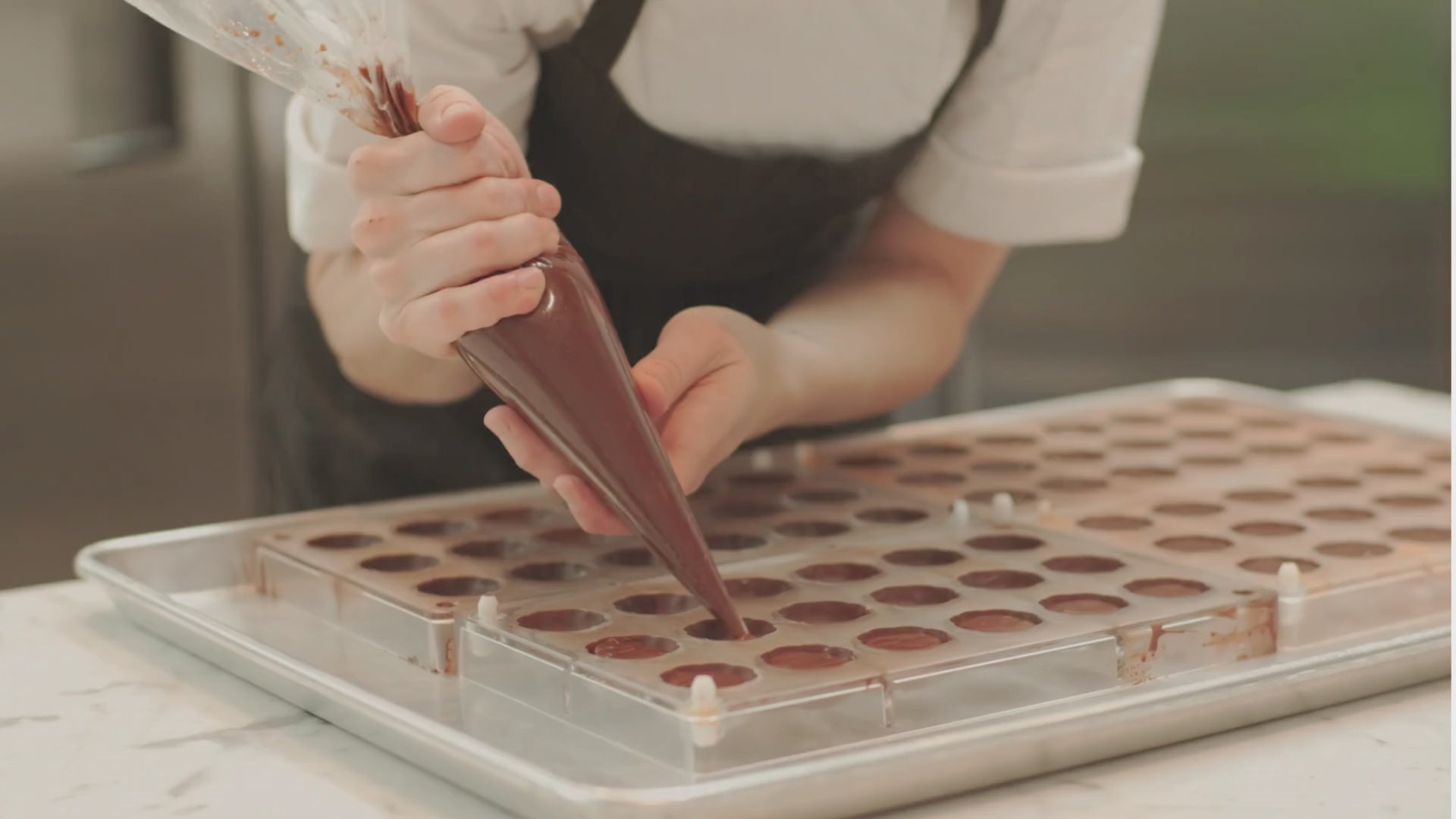 Chocolate being piped into molds, then formed into exquisite bon bons